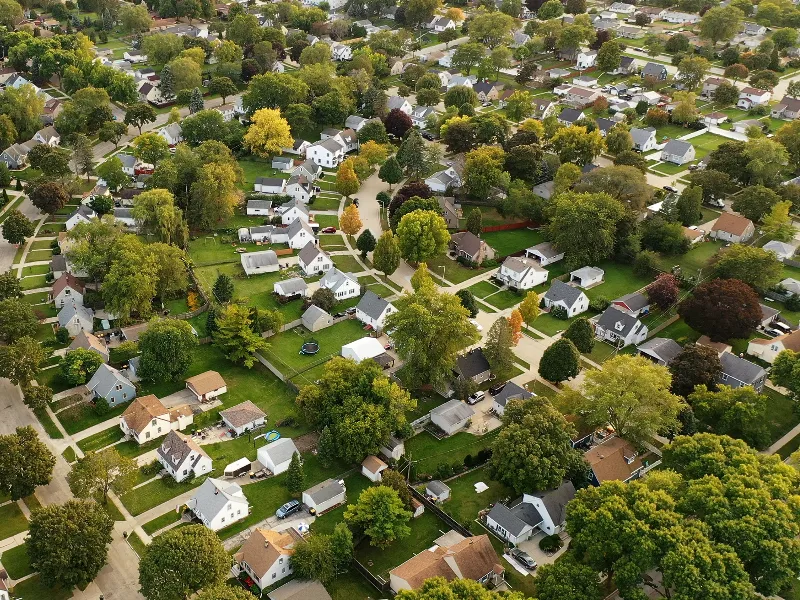 Aerial view of a suburban neighborhood with houses, trees, and green lawns.